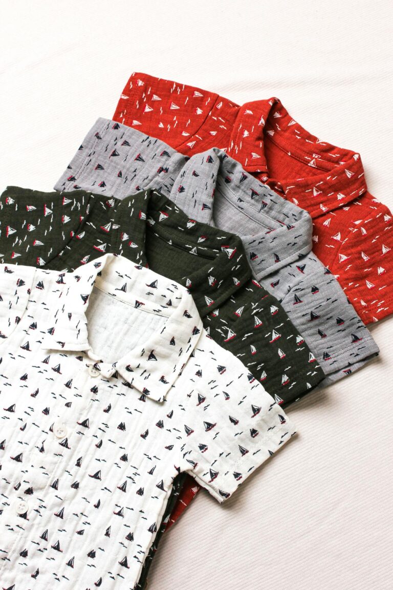 A collection of baby shirts in various colors with ship patterns, perfect for fashion-forward kids.