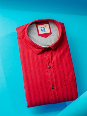 A vibrant red polo shirt neatly folded on a striking blue surface, captured from above.