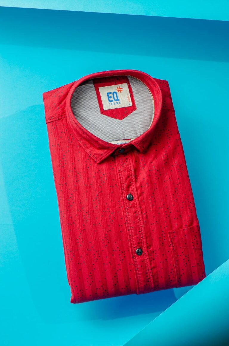A vibrant red polo shirt neatly folded on a striking blue surface, captured from above.