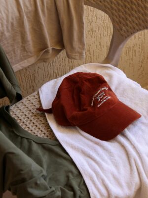 Casual clothes and a red cap laid out on a patio chair with natural light.