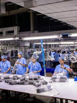 Group of blue collar workers organizing textiles in an Indian factory setting.