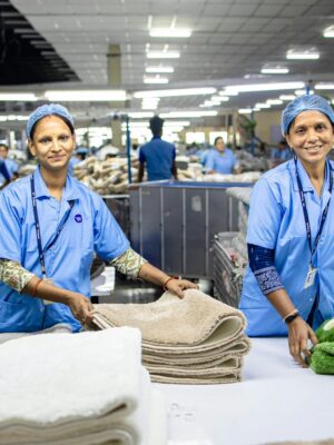 Two female workers in a textile factory sorting and organizing towels on a production line.